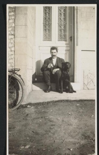 Man with a moustache sitting in front of a door with dog Myra