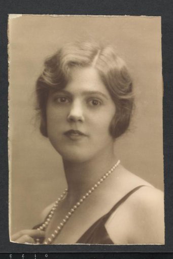 Portrait of G.A. Urtebise with short hair, dress with narrow straps and pearl necklace