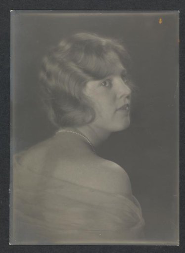 Portrait of G.A. Urtebise with short hair, pearl necklace and fabric draped around bare shoulders