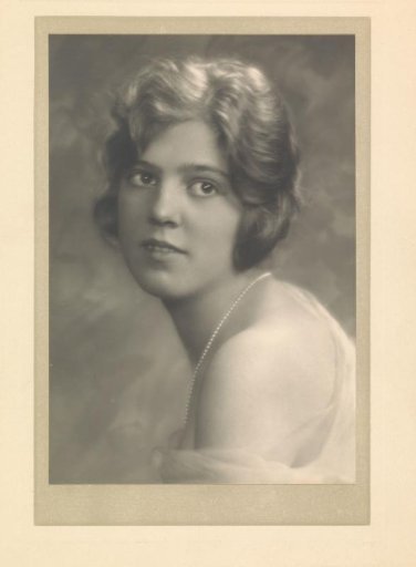 Portrait of G.A. Urtebise with short hair, pearl necklace and fabric draped around bare shoulders