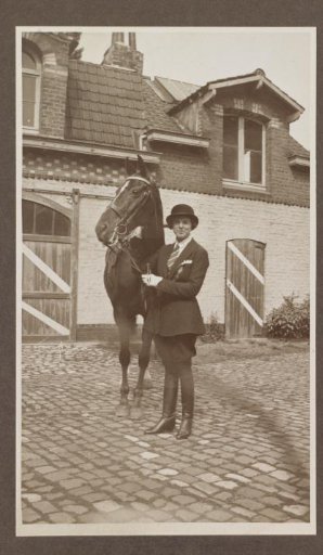 G.A. Urtebise in an equestrian costume standing by a horse