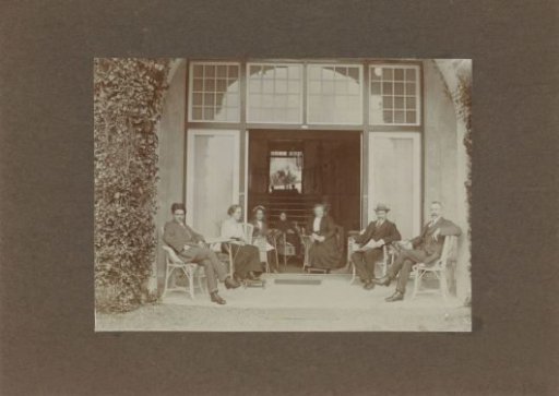 Men, Women, and Children Posing on a Veranda; in the Background, the Photographer is Visible in a Mirror