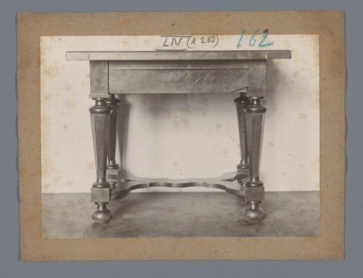 Table with legs in the form of stylized columns connected by a double Y-shaped cross