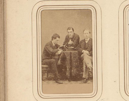 Three men at a table, including one reading man