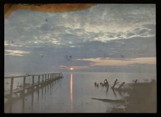 Sunset over water, with a pier on the left and more piles on the right