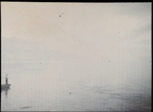 View over water, with a man standing in a boat at the far left