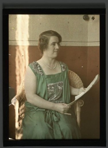 Portrait of Tine sitting in a chair, holding a sheet of paper, possibly sheet music