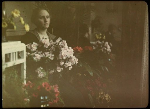 Portrait of Fifi in an interior, surrounded by flowers, with her reflection and that of Jacob Olie to the right