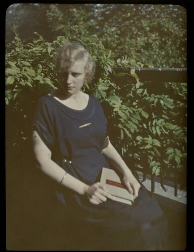 Portrait of Fifi seated on a balcony, with a book on her lap