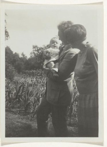Karl With holding a child in a garden, accompanied by an unknown woman