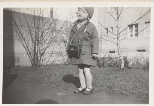 Child in a Winter Coat Standing in a Garden