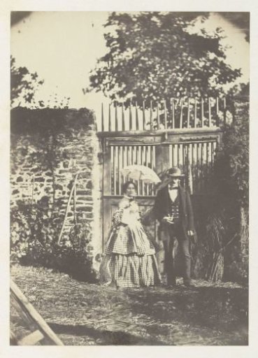 Portrait of an unknown man and woman with an umbrella, standing before a fence