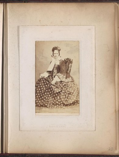 Portrait of a woman in a long spotted dress holding an umbrella