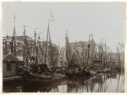 Boats in the Damrak, decorated with flags for the inauguration of Queen Wilhelmina