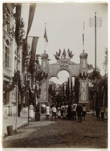 View of an arch of triumph and a decorated street, possibly for the visit of Queen Wilhelmina and Prince Hendrik to Amsterdam