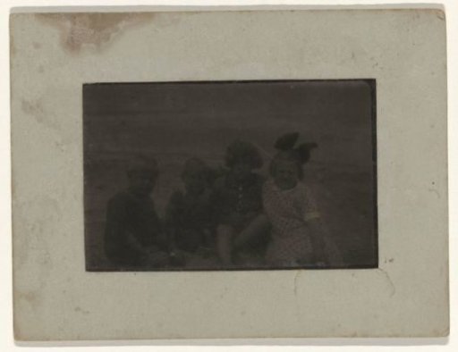 Group portrait of two unknown boys and two unknown girls sitting on the beach at Valkeveen
