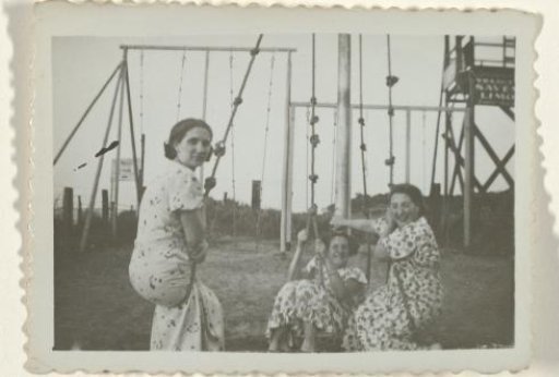 Three women on swings on the beach at Valkeveen