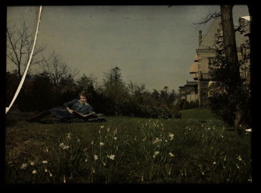 Portrait of a girl, possibly Elise Burdet, lying in the grass at the country house Nieuwe Lindenheuvel in Overveen
