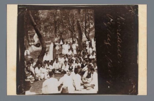 Sitting people, especially dressed in white, during a ceremony (?) among the trees, Korea