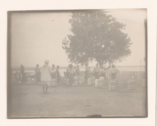Men with white turbans by the water, engaged in bringing or fetching boxes or cans, South-East Asia