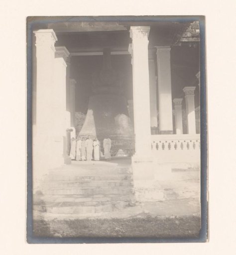 People posing near a bell, part of a Buddhist shrine, Myanmar