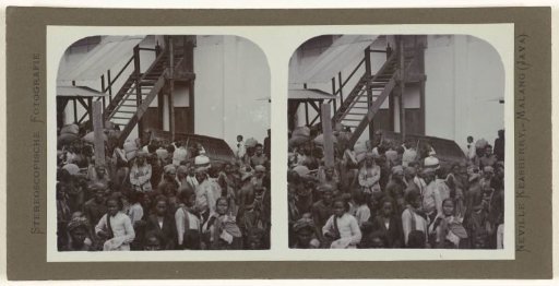 Javanese workers carrying coffee harvest in large sacks on their backs.