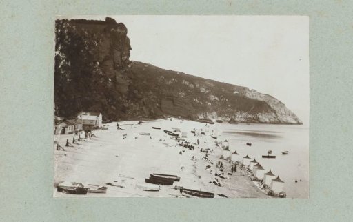 The beach at Babbicombe with beach huts and rowing boats.