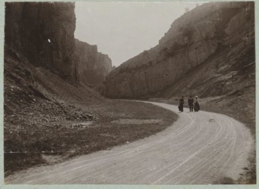 Three Walkers on a Road Winding Through Rocks