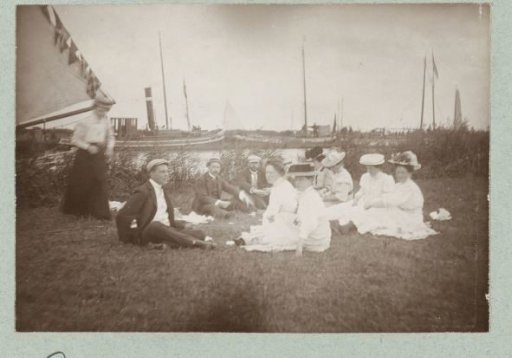 Picnicking people on a grassy field near the water