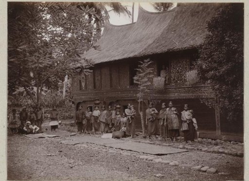Group portrait of unknown women and children in front of a Minangkabau house