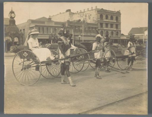 Four rickshaws and their bearers, one with a woman as passenger