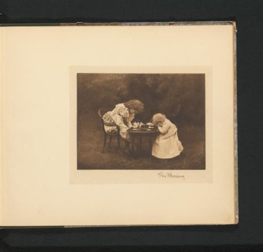 Two girls praying at a table in a garden with a toy tea set on it