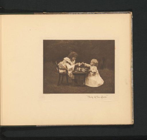 Two girls at a table in a garden, the eldest pouring tea into a cup of a toy tea set
