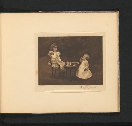 Two girls drinking tea from a toy tea set at a table in a garden