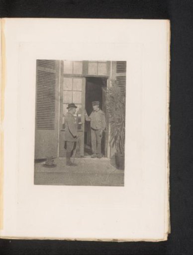 View of two unknown men, one of whom is standing in the doorway