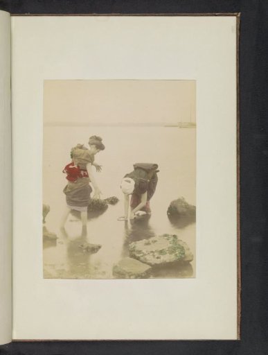 Two girls collecting shellfish on a beach in Japan