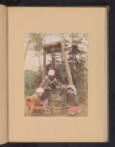Three women washing rice at a well