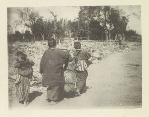 Two women carrying belongings across a road in Japan after an earthquake