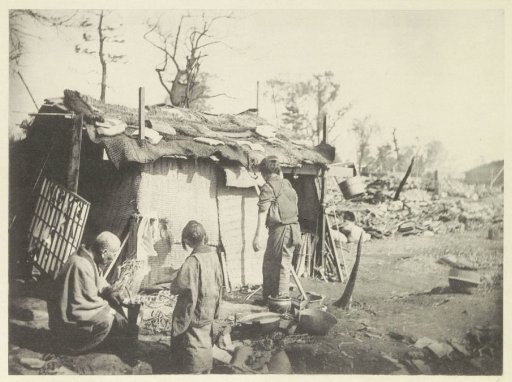 Two women and a man in front of a temporary dwelling in Japan