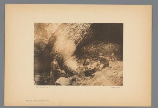 Four men and a woman sitting by a rock wall
