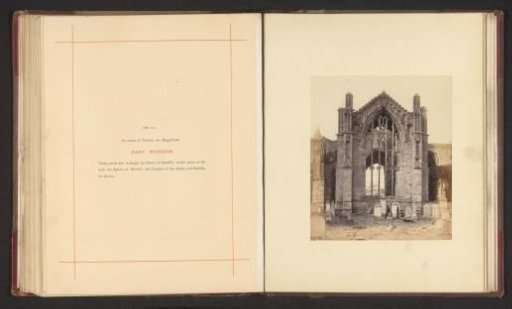 View of a window of the ruins of Melrose Abbey with two men in front of it