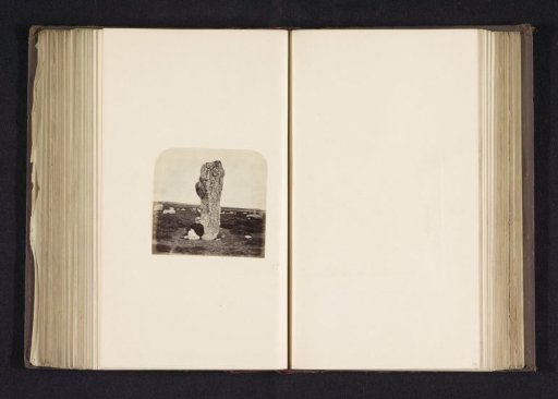 Man sitting against a menhir in a field in Ménec