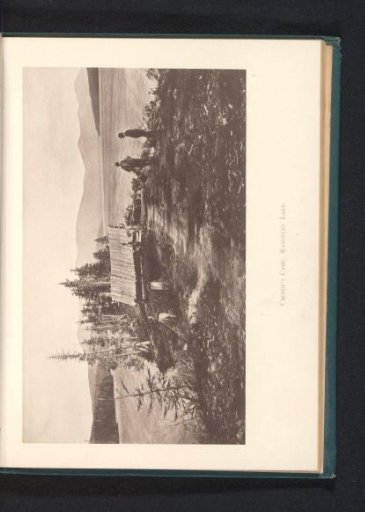 Three men at a hut, with Rangeley Lake in the background