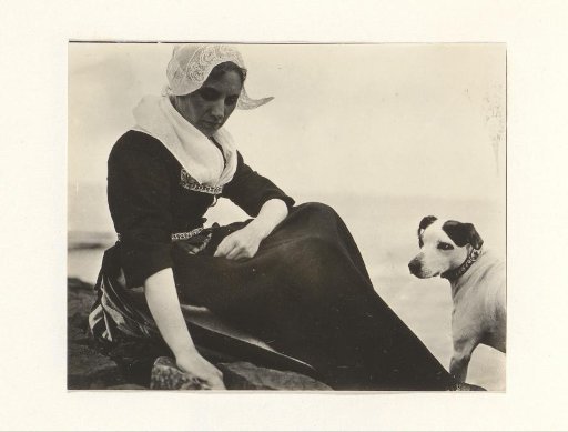 Woman in traditional dress with a dog by the water