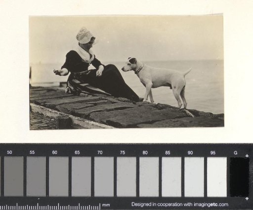 Woman in traditional dress with a dog by the water
