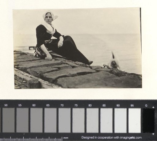Woman in traditional dress with a dog by the water