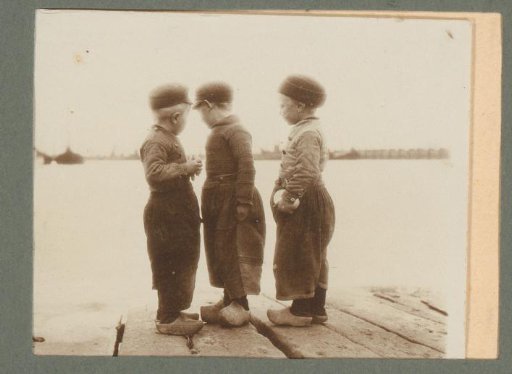 Three boys in traditional dress standing on a jetty by a lake