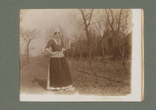 Woman in traditional dress, standing among bare trees