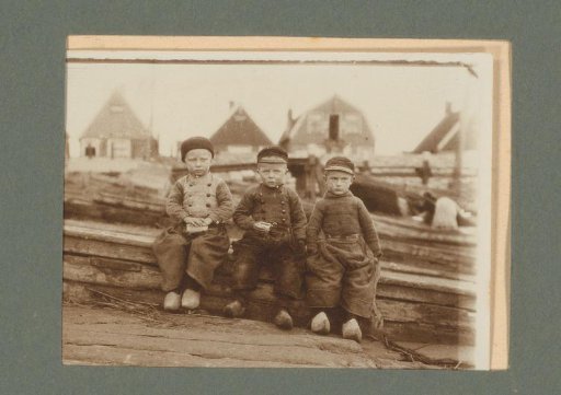 Three boys in traditional dress, sitting on a pair of benches