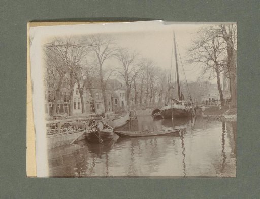 View of rowing and sailing boats on a waterway near a city or village